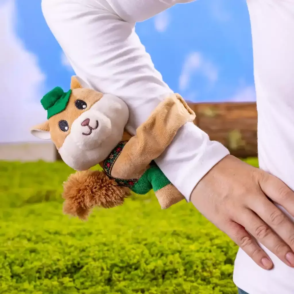 Esquilo de pelúcia Abraçadinho Nutty Bavarian e Criamigos abraçado ao braço de uma pessoa.